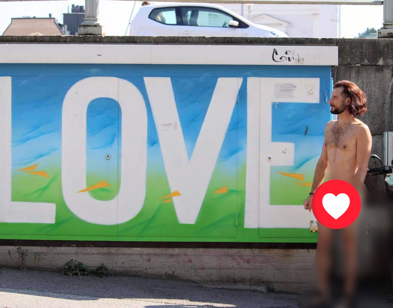 A naked man in front of a graffiti text: "Love"